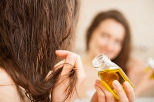 lady applying olive oil on her long hair