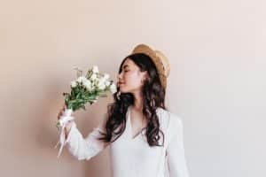 Lady with curly hair smelling a bouquet of flowers