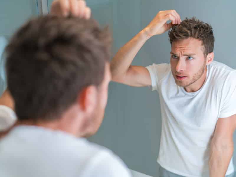 man checking hair on mirror